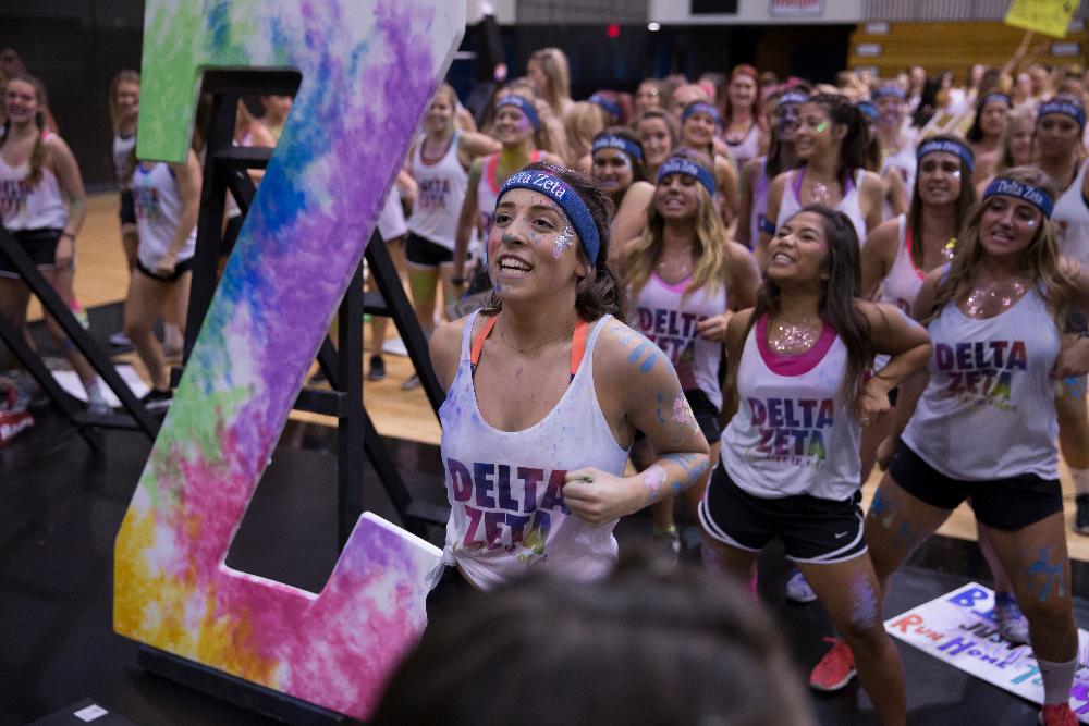 Sorority sisters wearing "Delta Zeta" shirts with paint all over their faces